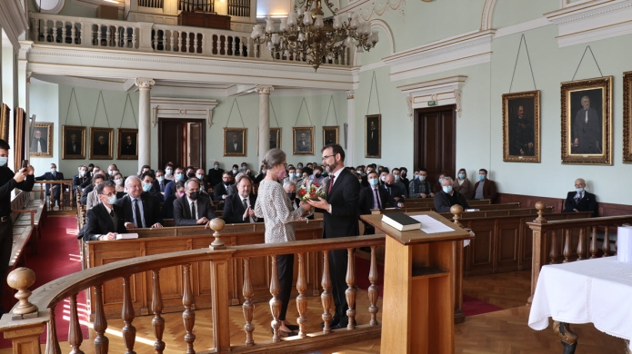 A rektor Adorjáni Mária számára egy csokor virágot nyújt át